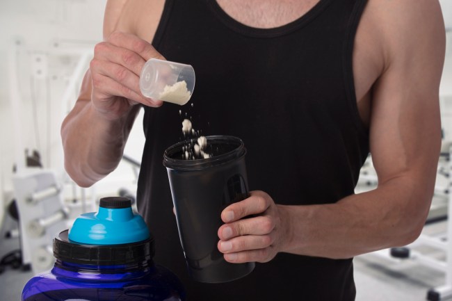Weight gain. Man put whey protein with amino acids bodybuilding dietary supplement in shaker. Fitness, muscle recovery and sport concept.