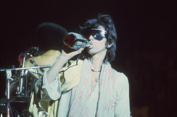 Guitarist Keith Richards having an alcohol drink while on stage during the Rolling Stones' 1975 Tour of the Americas. (Photo by Christopher Simon Sykes/Hulton Archive/Getty Images)