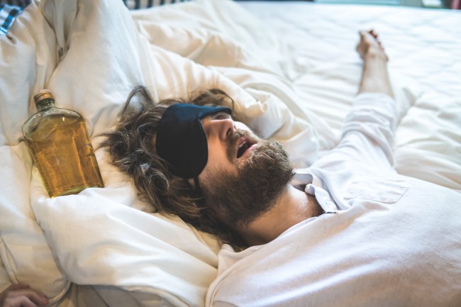 Guy passed out in bed after drinking alcohol excessively. The day after hangover and intoxication.