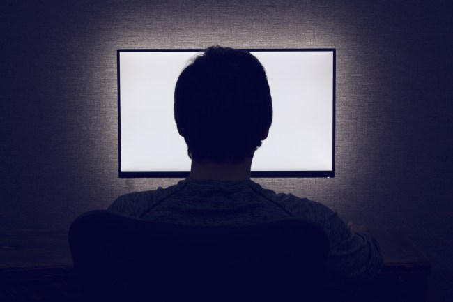 Man sits in front of a blank monitor in dark room