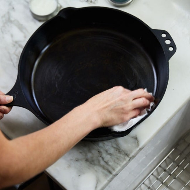 Smithey Ironware cast iron skillet being cleaned with soap by hand.
