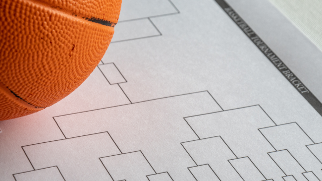 A basketball rests atop an NCAA Tournament bracket.
