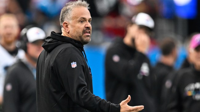 Matt Rhule talks to someone on the field while coaching the Carolina Panthers.