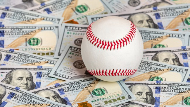 A baseball sits on a pile of money.