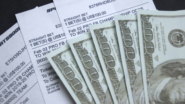 Money spread out on a stack of betting slips.