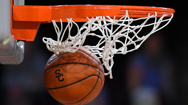 A Southern California logo on a basketball going through the net.