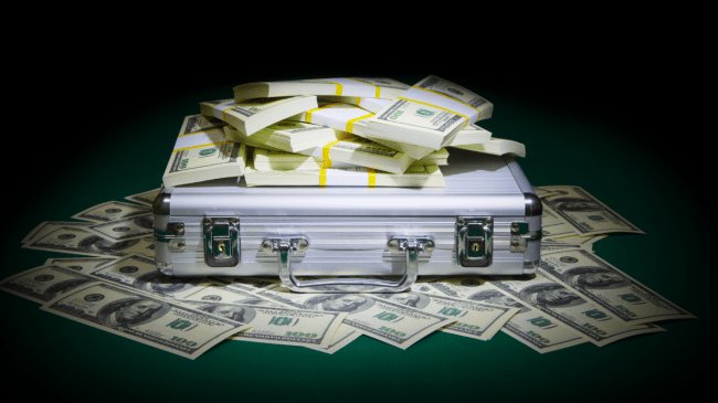 Stacks of money sit atop a suitcase.