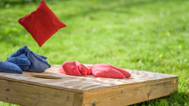 A bag drops onto a cornhole board.