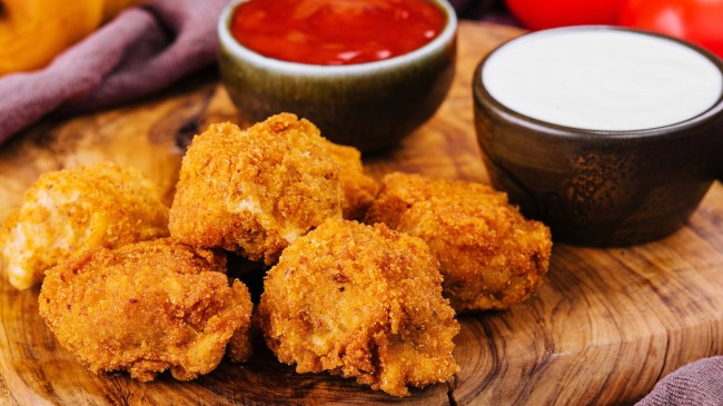 Chicken fingers next to a dipping sauces.