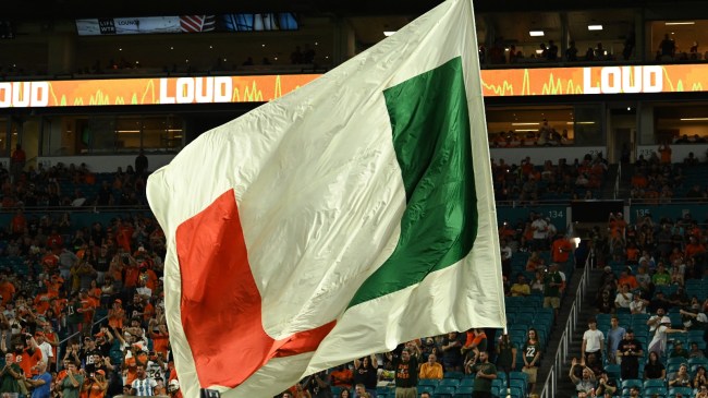 A Miami cheerleader carries a flag with a Hurricanes logo.