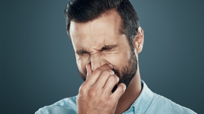 Man holding in sneeze