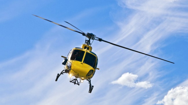 A yellow helicopter flies through the air.