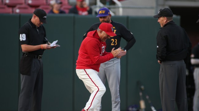 ECU coach Cliff Godwin and NC State's Elliott Avent speak to the umpiring crew before a baseball game.