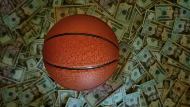 A basketball sits atop a pile of cash.