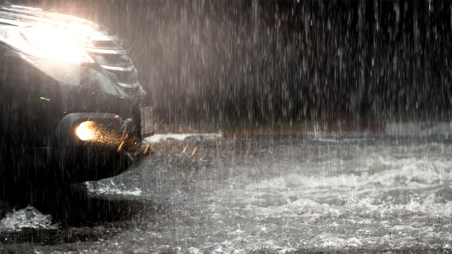 Car-with-headlights-run-through-flood-water-during-hard-rain
