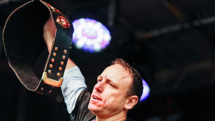 Joey Chestnut holding up championship belt