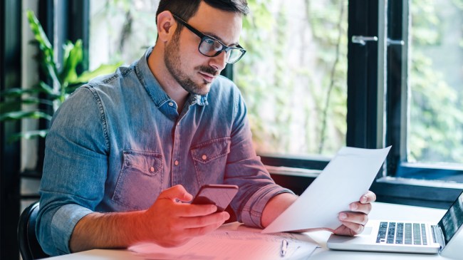 man-in-office-holding-his-phone