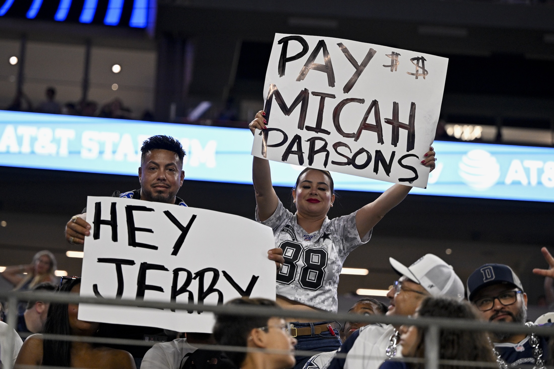 Aug 16, 2025; Arlington, Texas, USA; Dallas Cowboys fans hold up signs to owner Jerry Jones and defensive end Micah Parsons (11) during the second half of the game against the Baltimore Ravens at AT&T Stadium. Mandatory Credit: 